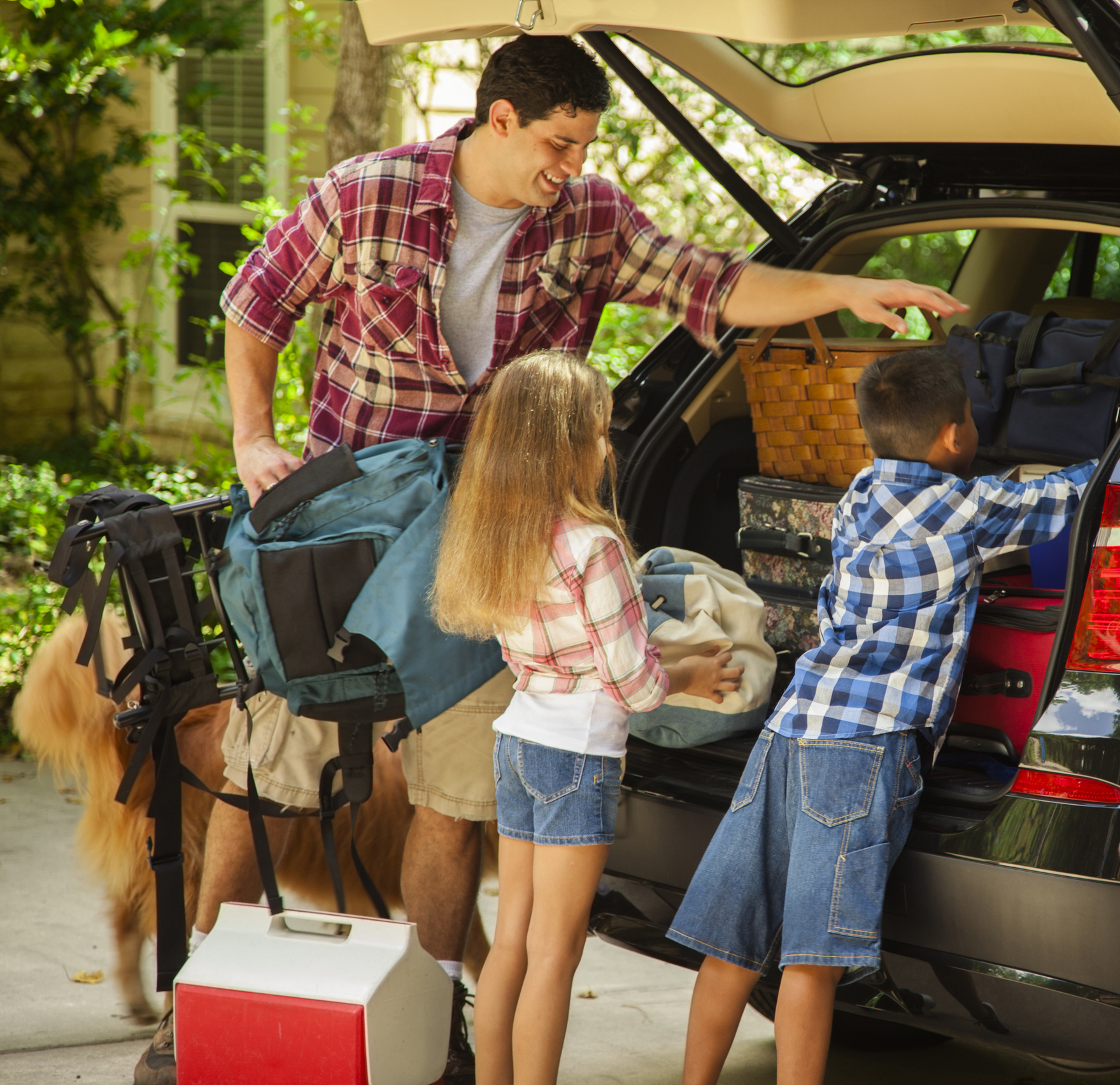 Family packing car to go on vacation. Father, children.